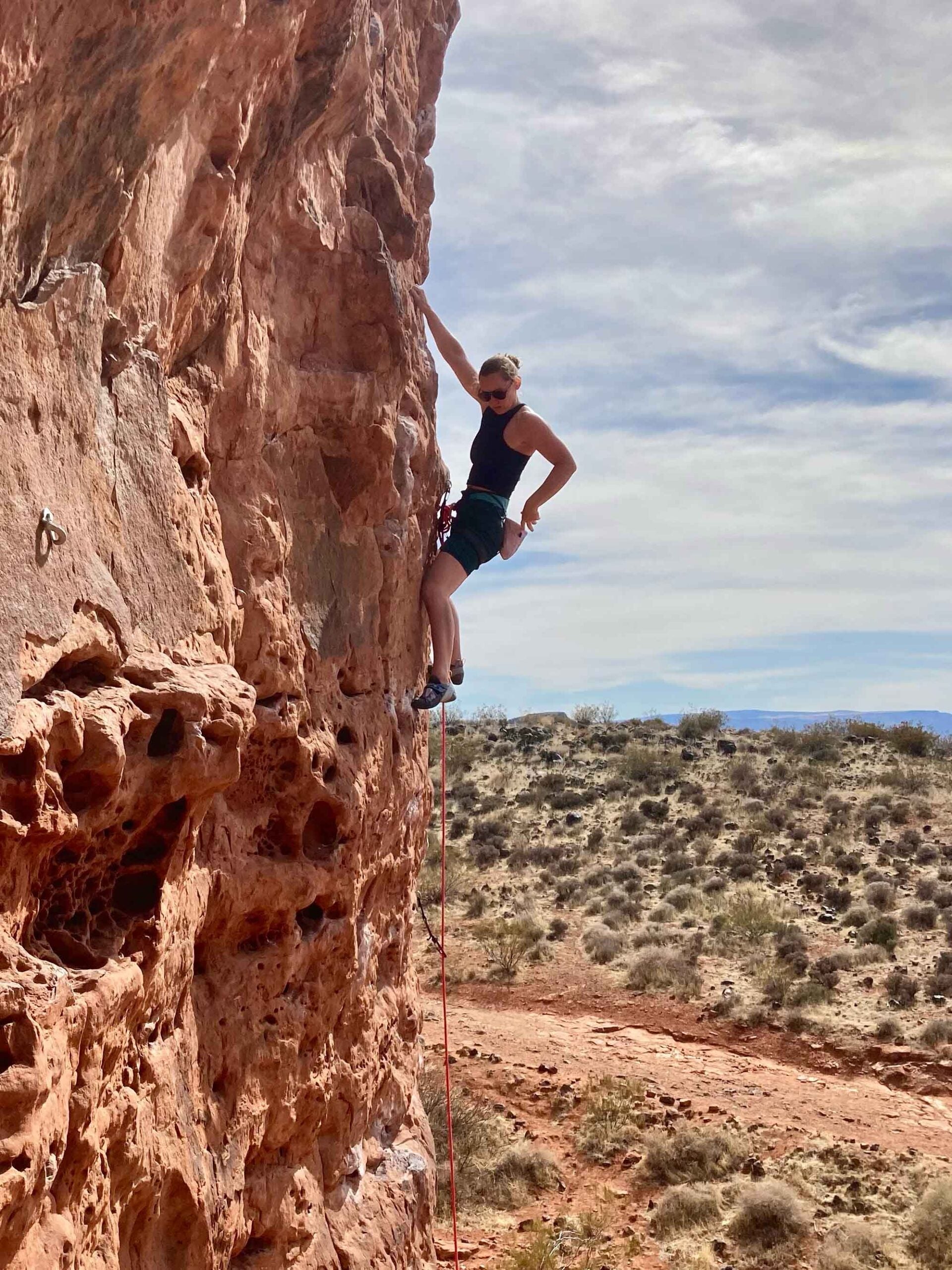 Hannah Smith climbs up a vertical rock outdoors.